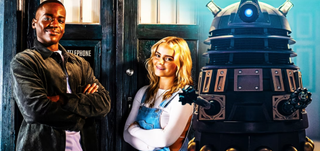 The Fifteenth Doctor (played by Ncuti Gatwa) and his companion Ruby Sunday (Millie Gibson) pose in front of the Tardis as a dalek looms nearby