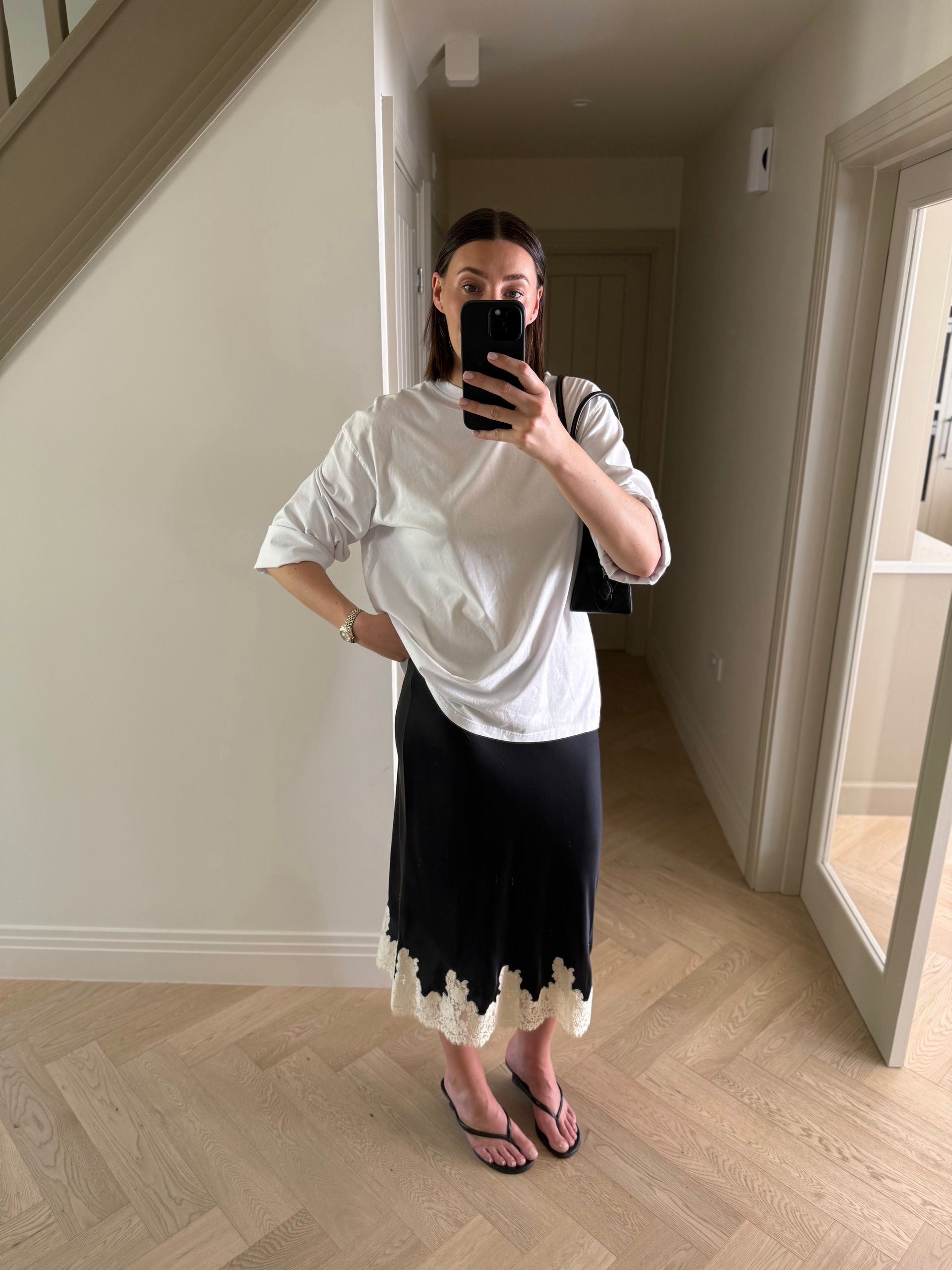 @sarahlouiseblythe wearing a lace-trim skirt and wedge sandals.