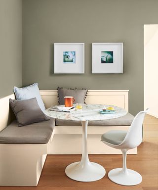 dining nook with pewter walls and white bench corner seat and marble round table