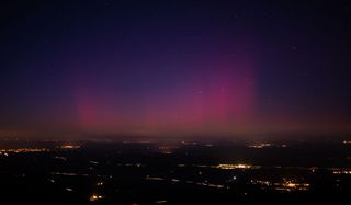 bands of northern lights fill the sky colored pink, red and purple.