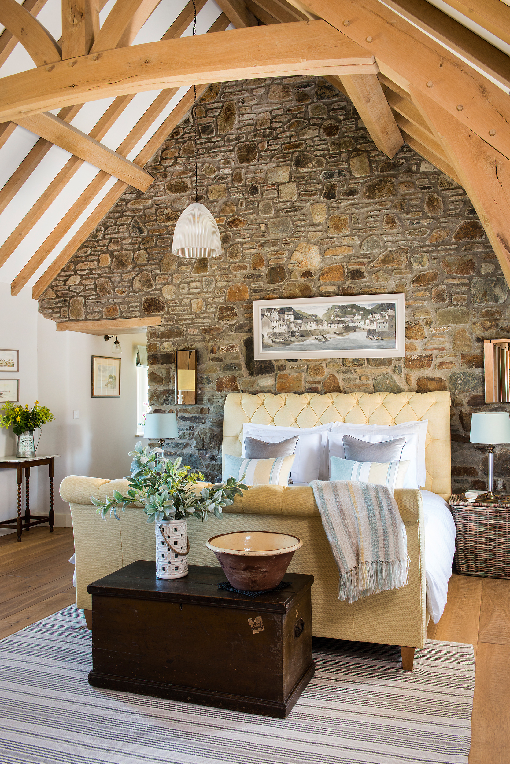 welsh long house bedroom with exposed beams and stone wall