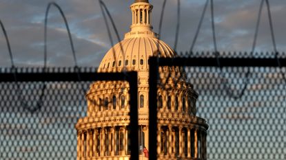 The US Capitol is seen behind a fence with razor wire.
