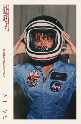 a woman in a blue flight suit puts on an astronaut helmet