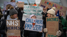 Striking NHS workers pictured with signs. One reads ‘call us hero, pay us zero’