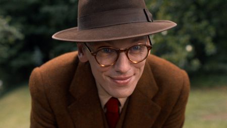 Jamie Campbell Bower as Mr. Whatsit kneeling down in Stranger Things. 