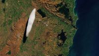 A satellite photo of a single elongated white cloud hovering over New Zealand