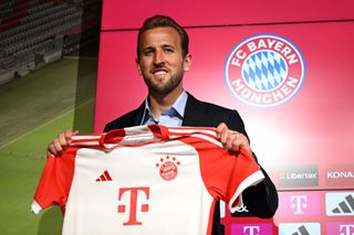 Harry Kane of FC Bayern München poses for a photograph whilst holding a FC Bayern München shirt after speaking to the media during an official press conference announcing his signing with the club at Presse Club of Allianz Arena on August 13, 2023 in Munich, Germany. The English National forward signed a contract with the club until 2027. (Photo by Christian Kaspar-Bartke/Getty Images)