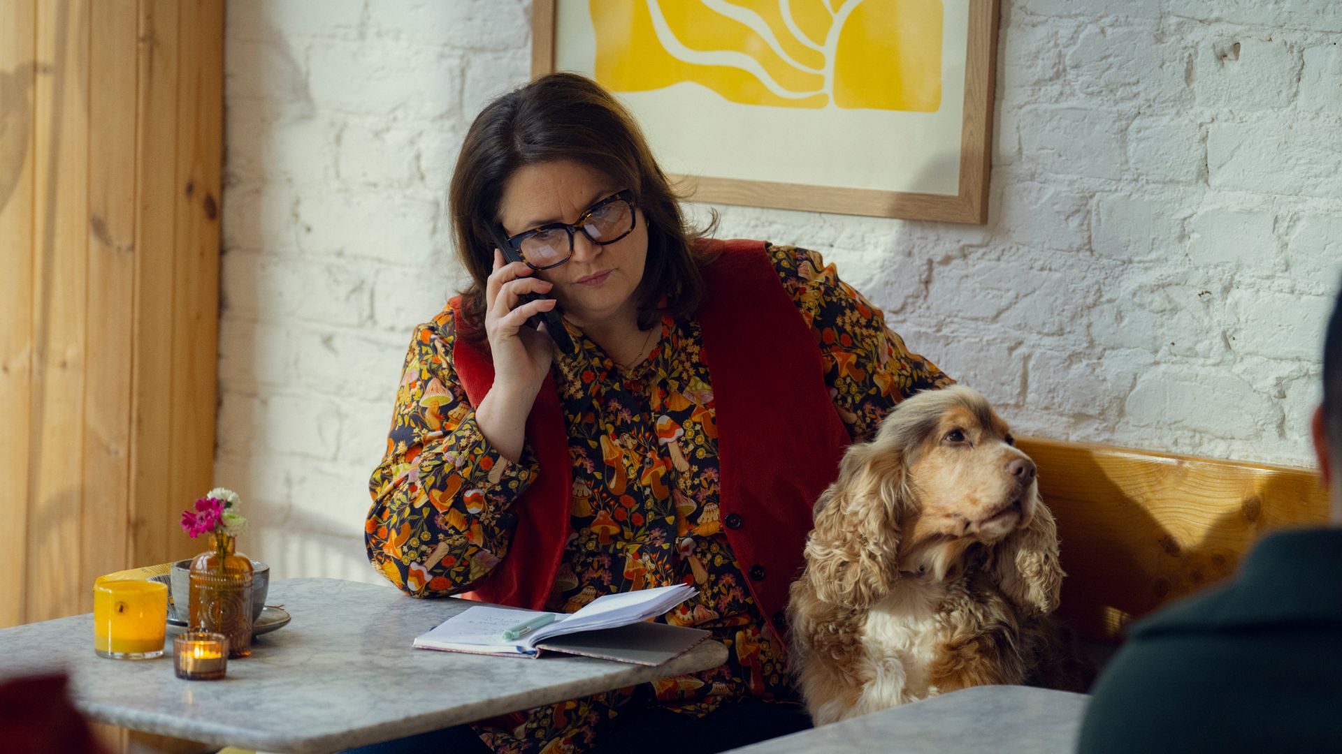 Elena takes a phone call while petting a dog