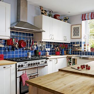 kitchen room with blue splashback tiles white cabinet and gas stove