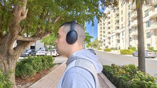reviewer wearing Bose QC headphones testing sound quality