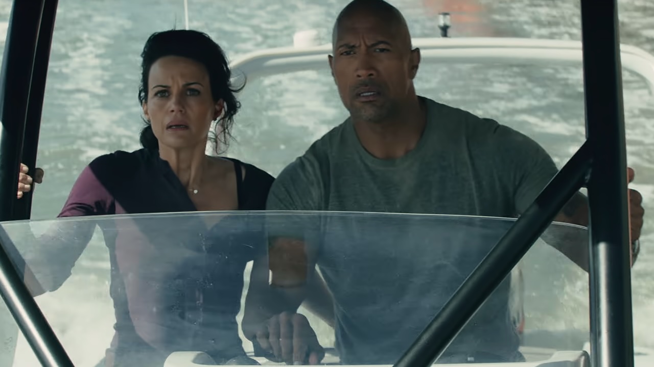 Carla Gugino and Dwayne Johnson looking scared on a boat. 
