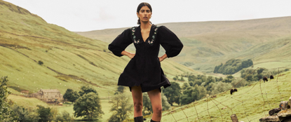 Model wearing nobody's child black dress with puff sleeves with British rolling hills in the background