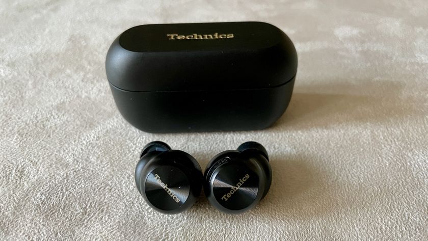 Technics EAH-AZ100 earbuds in black, on a beige background, held in a hand