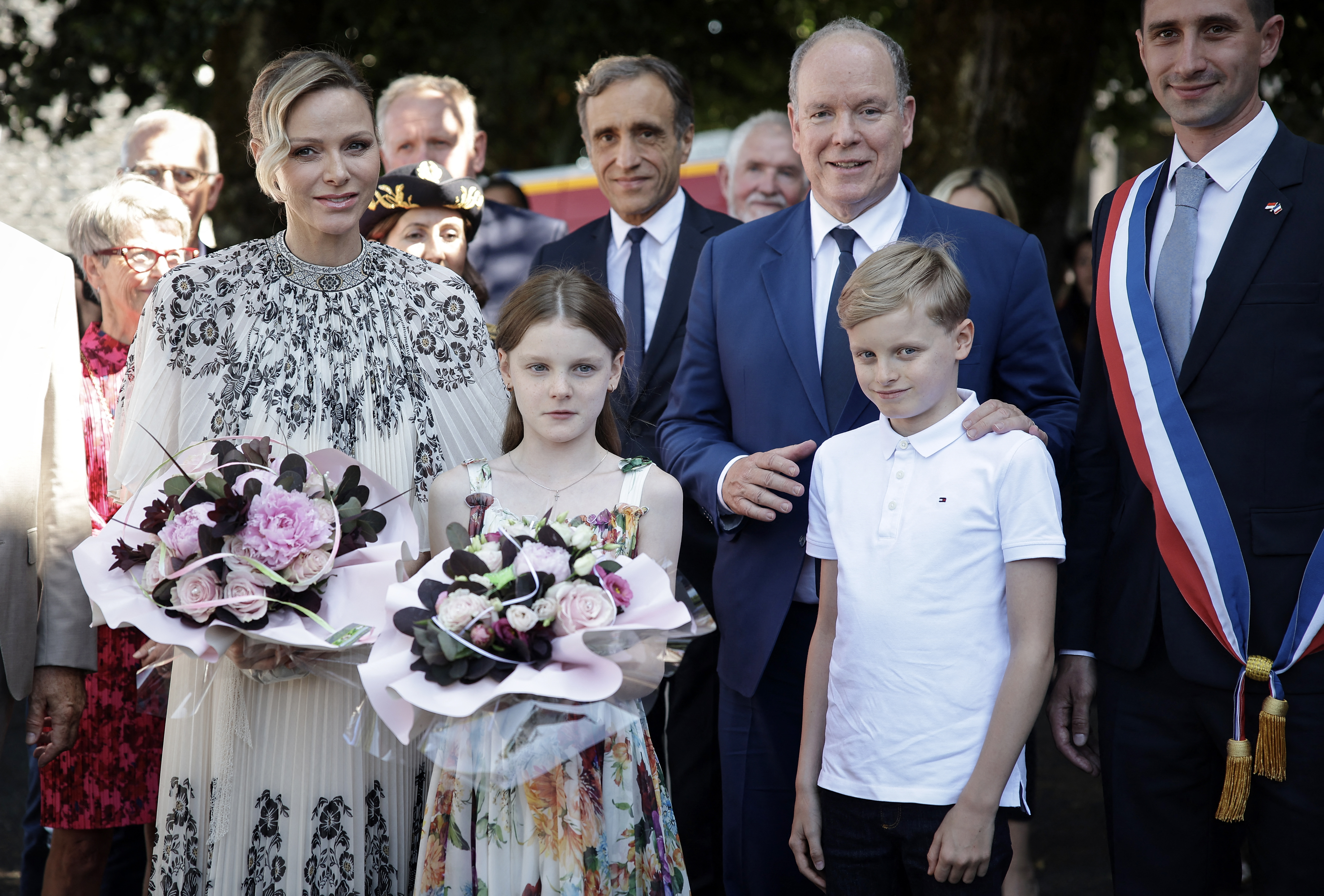 Prince Albert, Princess Charlene and their twins holding flowers and smiling
