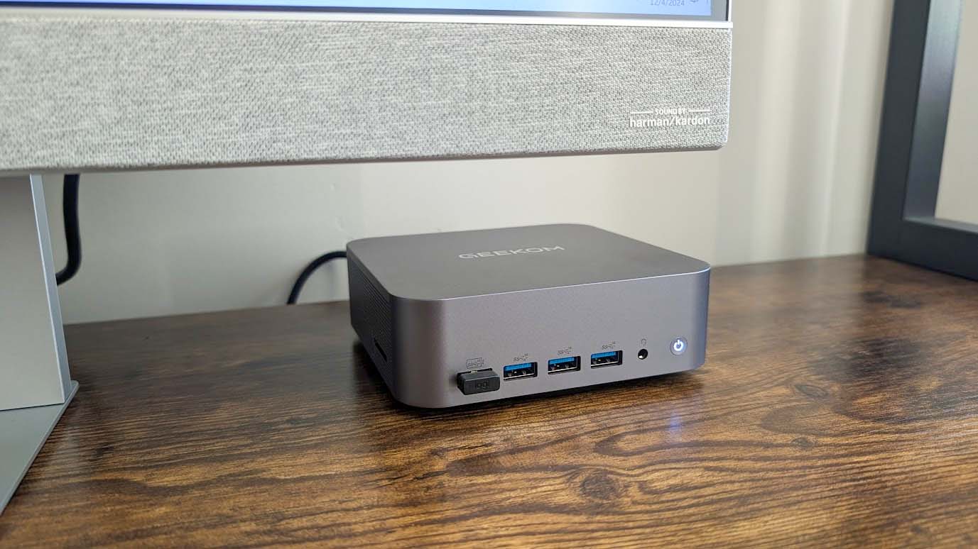 Geekom GT1 Mega connected to monitor and sitting on a desk.