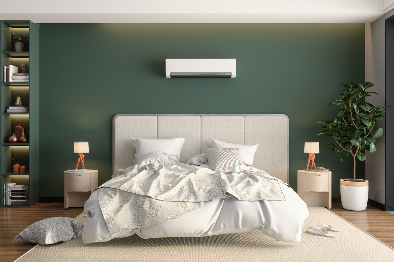 A modern bedroom, a bed with unmade sheets, and an aircon machine on the wall