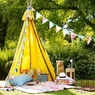outdoor party with bunting flag and teepee tent with cushion