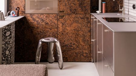 a burl wood kitchen with a chrome metal stool that looks like a deflated balloon