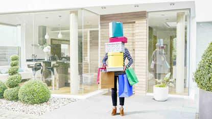 A woman holding a large pile of shopping boxes