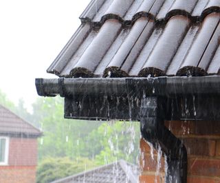 black gutter and roof with rain pouring down