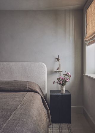 A neutral bedroom with a scalloped pendant bedside lamp and natural linen textures