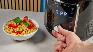 a black smart home enabled wi-Fi instant pot with a touchscreen and a 6QT inner pot is photographed against a blue background