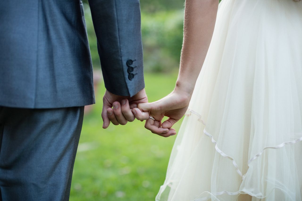 Wedding couple tentatively holds hands