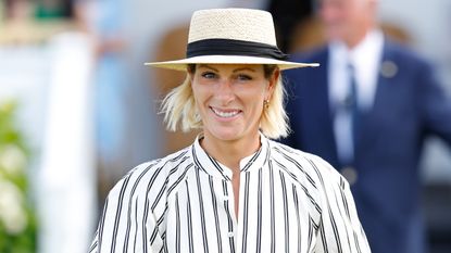 Zara Tindall, wearing a sunhat and striped dress, attends the Out-Sourcing Inc. Royal Windsor Cup Final polo match and a carriage driving display on June 22, 2025