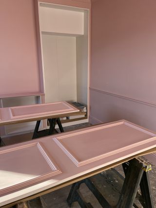 A pink color drenched bedroom in process of fitting a pink ikea pax closet