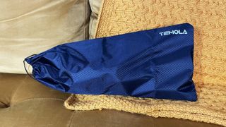 The Temola TS20BS handheld vacuum inside the storage bag on a mustard color blanket and sofa.