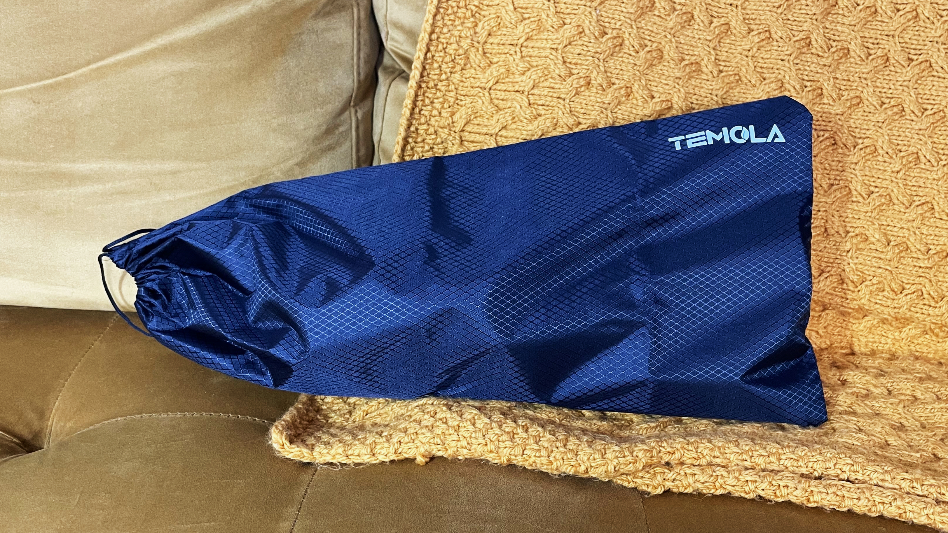 The Temola TS20BS handheld vacuum inside the storage bag on a mustard color blanket and sofa.