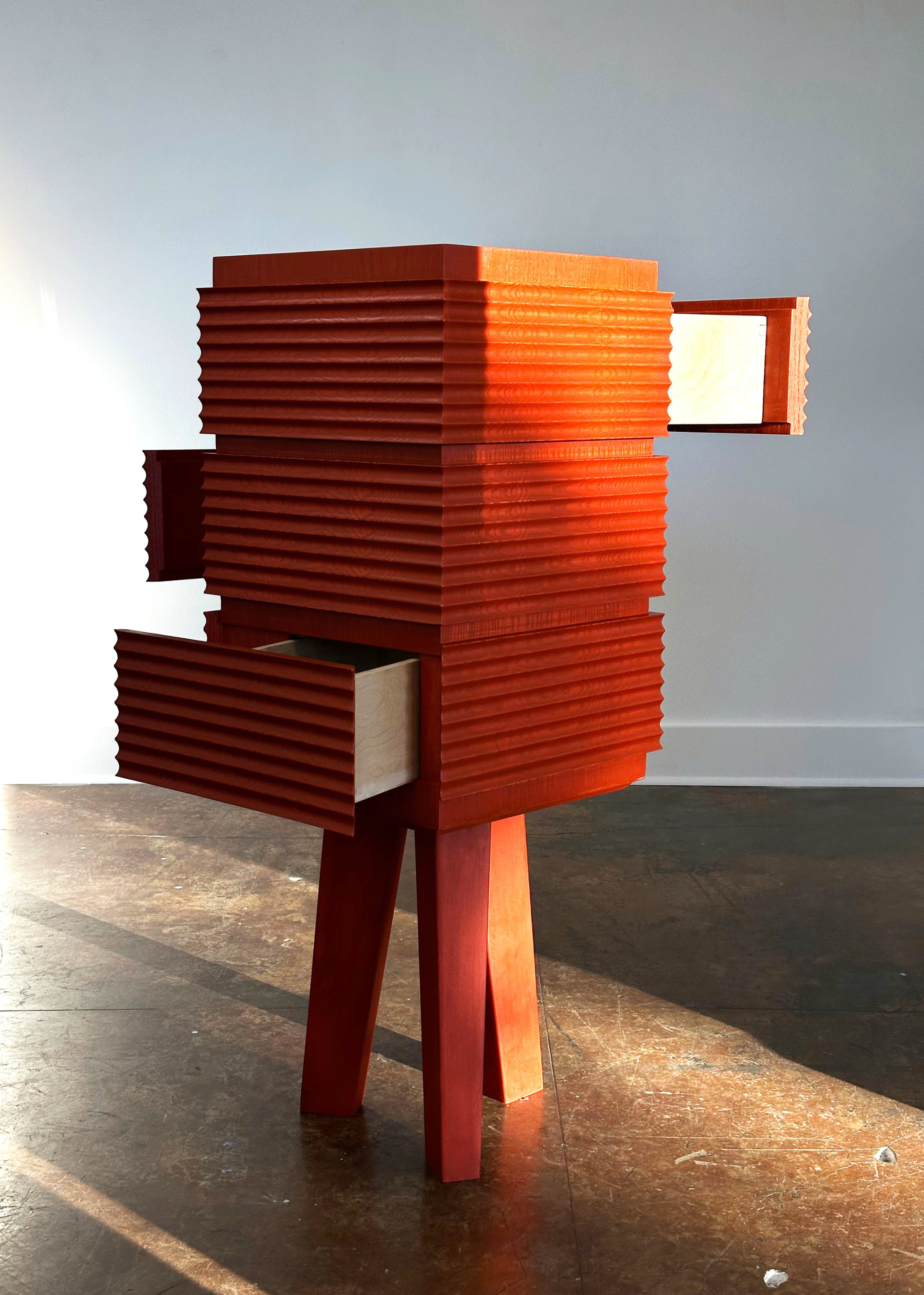 A ridged orange table with three legs and drawers pulled out in different directions