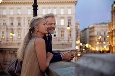 A couple leaning against a balustrade overlooking Vienna during the evening.