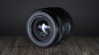 Canon RF 50mm f/1.8 STM on a table, against a dark backdrop