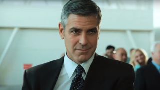 George Clooney wears a sly smile while standing in the airport in Up In The Air.