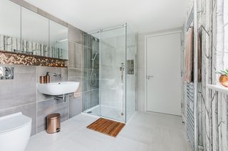 bathroom with grey tiles, a modern shower, copper accents and patterned wallpaper
