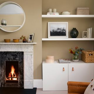 Neutral living room with white storage, marble fireplace and round mirror