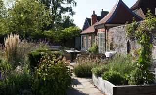 walled garden with raised beds of herbs near coach house