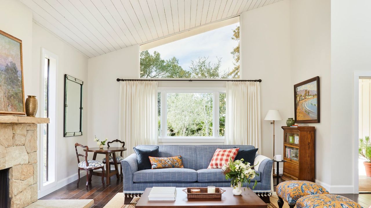 living room with blue sofa and sloping glass window and white walls