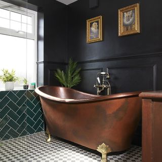 black bathroom with copper bath and gold gilt frames