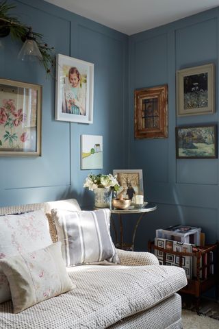 blue walls in living room with artwork alongside sofa with cushions