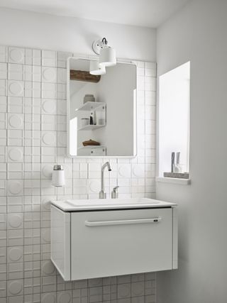In the bathroom, geometric white tiles and a freestanding minimalist sink with Vipp mirror and wall lamp