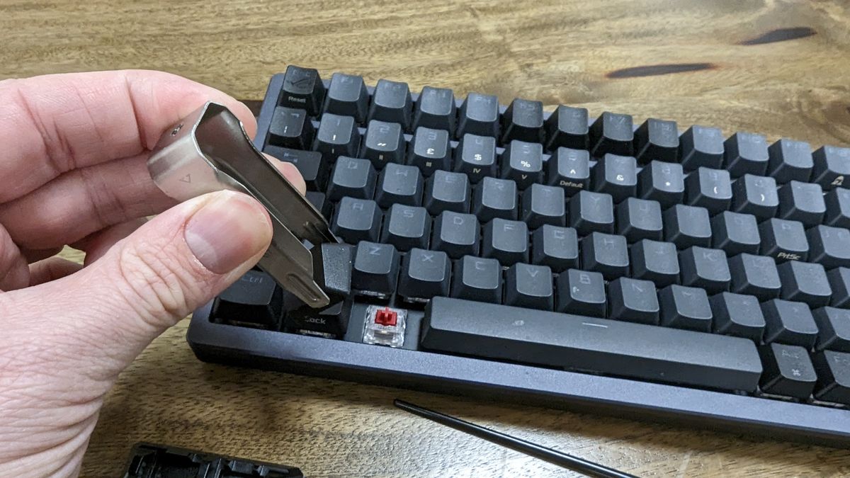 Asus ROG Azoth wireless gaming keyboard with RGB lighting on a wooden desk