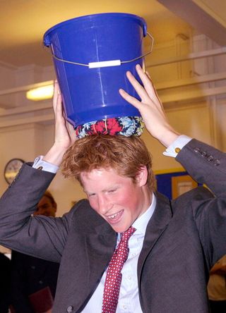Prince Harry Practices Carrying A Bucket Of Water On His Head
