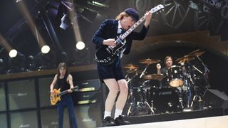 AC/DC guitarist Angus Young holding his Gibson SG in the air
