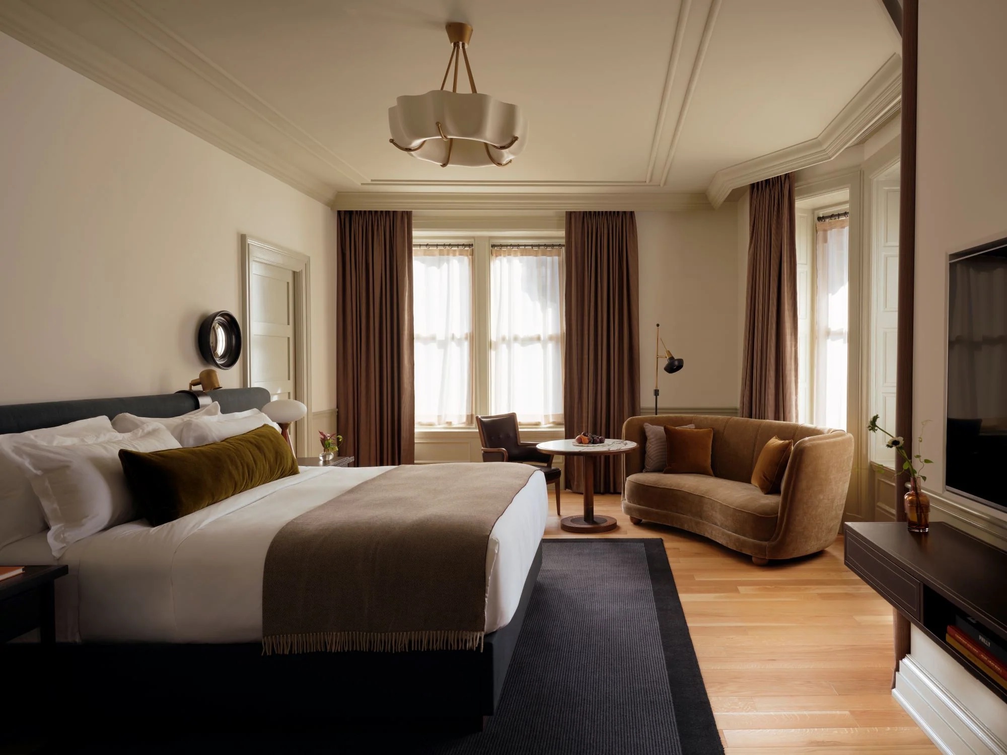 A contemporary bedroom with seating area on one side and media unit on the other