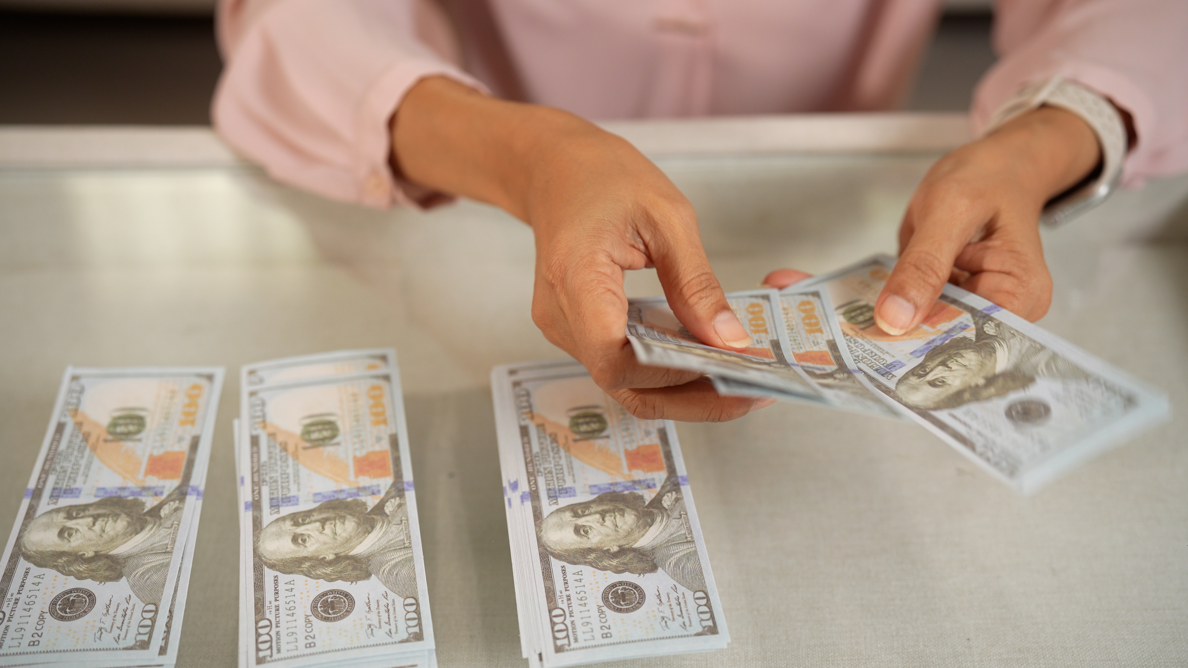 female counting one hundred dollar bills