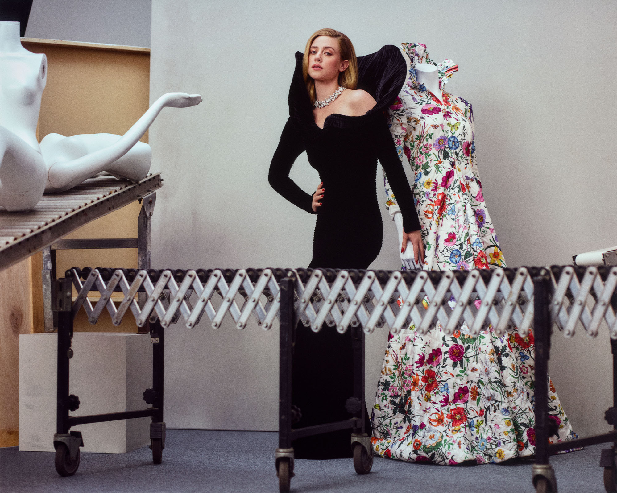 Forbidden Fruits actor Lili Reinhart for the Who What Wear 2026 Spring Issue wearing a black dress with a diamond necklace in front a green background.