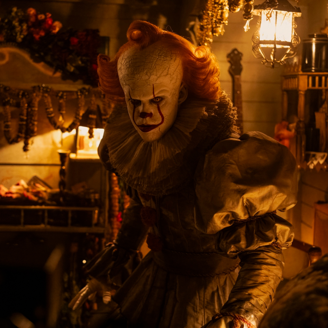 A scary clown (Bill Skarsgard as Pennywise) sits in a cluttered circus dressing room, in 'IT: Welcome to Derry.'