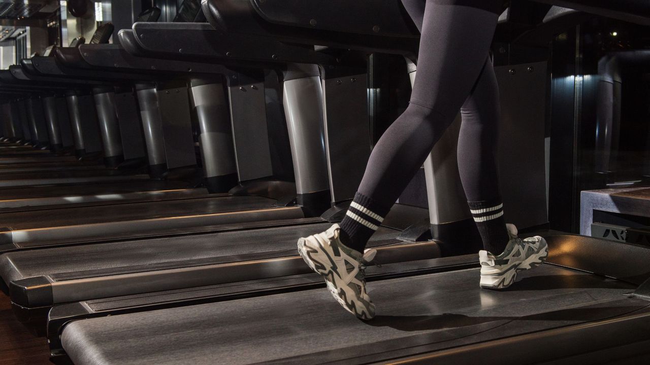 Woman&#039;s legs walking on treadmill in the gym
